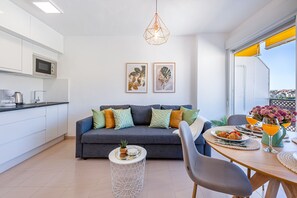 A modern kitchen with a microwave, coffee maker, and dining area with a table set for breakfast. - Cozy apartment in Naciones with beautiful view (Benalmádena)