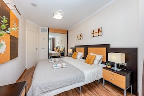 Ein modernes Hotelzimmer mit einem großen Bett, Nachttischen, einem Spiegel und Kunstwerken an den Wänden.