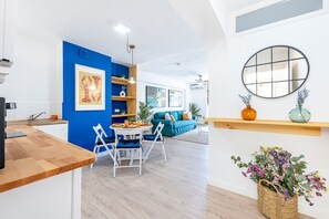 A modern kitchen with a blue accent wall, a dining area with a blue sofa, and a living room with a large mirror and decorative plants. - Penthouse with views in piscis (Benalmádena)