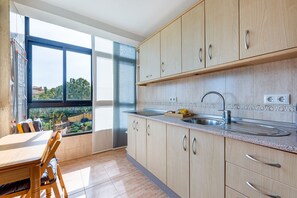 A modern kitchen with wooden cabinets, a stainless steel sink, and a window overlooking a garden. - Bright apartment in Aloha playa (Benalmádena)