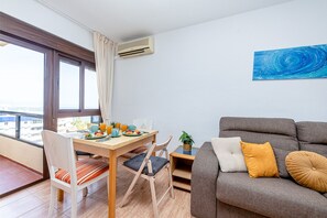 A modern living room with a dining area, a grey sofa, and a view of the city. - Bright apartment in Aloha playa (Benalmádena)