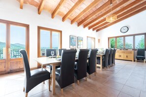 A dining area with a wooden ceiling, large windows, and a view of the outdoors.