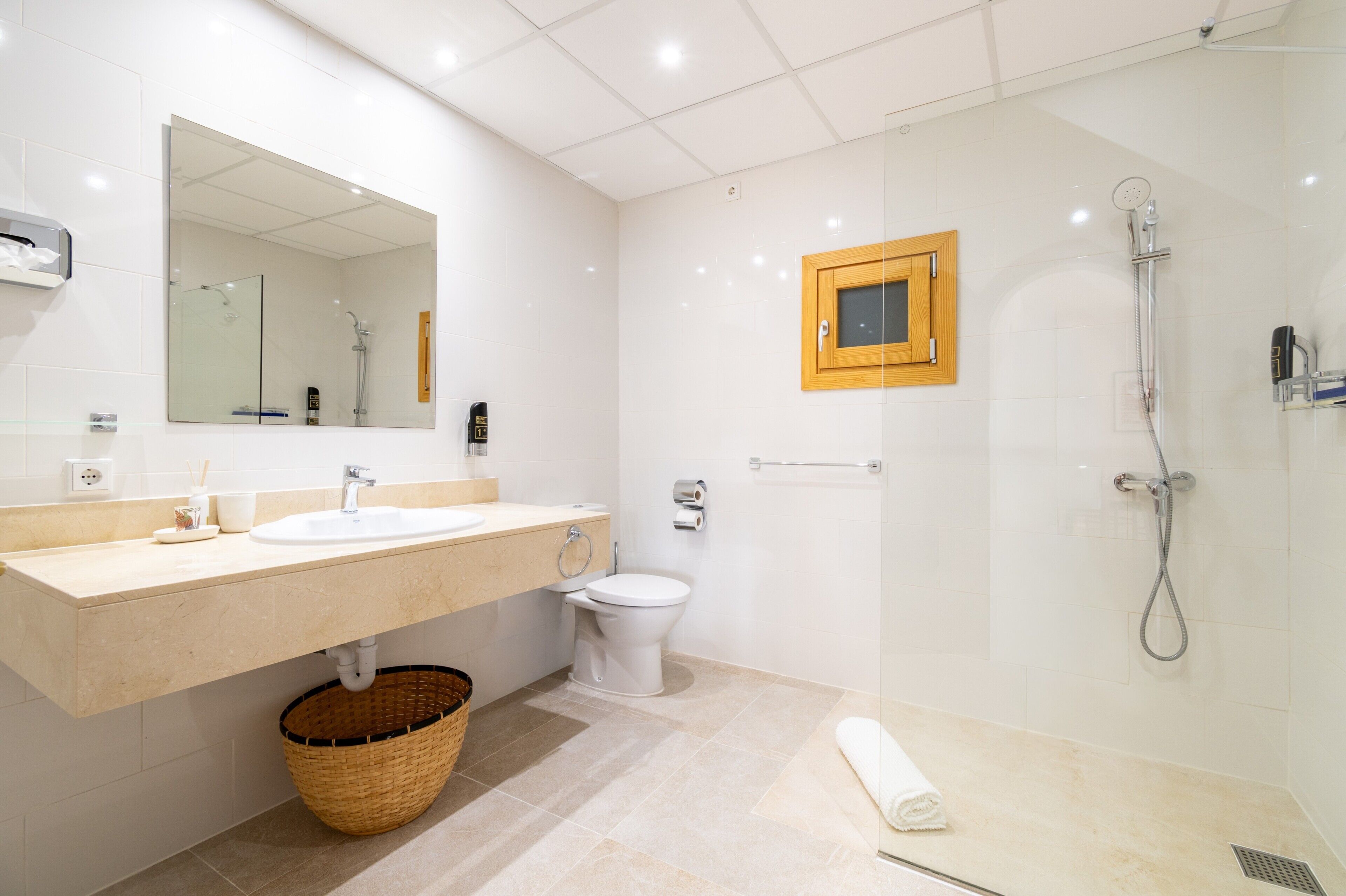 Ein modernes Badezimmer mit einem großen Spiegel, zwei Waschbecken, einer Toilette, einer Dusche und einem Handtuch auf dem Boden.
