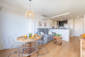 A modern living space with a dining area, grey sofa, clear chairs, a wooden table, and a kitchen in the background. - ISTVAN - Apartment with beautiful views (Benalmádena)