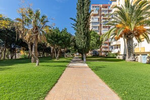 A pathway lined with trees and a multi-story building with balconies. - NICOLE - Flat in Iris with beautiful views (Arroyo de la Miel)