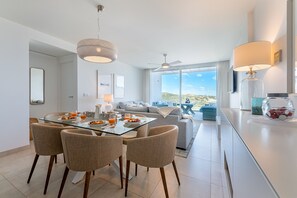 A modern dining area with a glass table, four chairs, and overhead lighting. - VIOLETA CB - Modern apartment with a beautiful view (La Cala de Mijas)