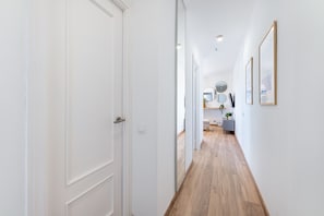 A narrow hallway with wooden flooring, white walls, and a door on the left. - Renovated apartment with beautiful views in Iris (Benalmádena)