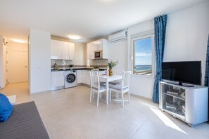 A compact living space with a kitchen, dining area, and a TV. - ANDREA 3 - Flat with sea view Jupiter (Benalmádena)