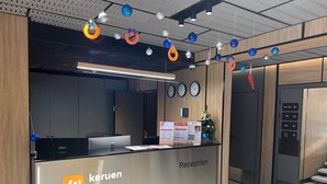 Un comptoir d’accueil avec une enseigne indiquant « Keruen Inn », une horloge et un ascenseur doté de boutons indiquant les directions.
