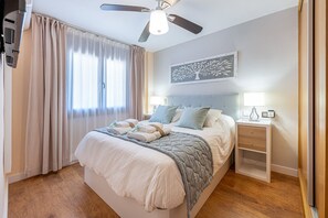 A bedroom with a bed, bedside tables, a ceiling fan, and a window with curtains.