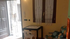Um quarto com cama, uma mesa com cadeira, um sofá e uma janela com cortinas.