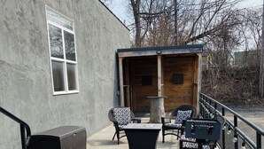 Un espace extérieur aménagé avec des meubles en osier, une porte en bois et un sol en béton.