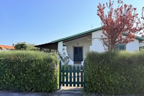 Un bâtiment blanc avec un toit vert, une porte noire et une petite fenêtre.