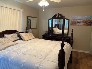 A bedroom with a large bed, a dresser, a mirror, and a painting on the wall. - Charming 2-bedroom house in beautiful Clearwater with AC washer dryer (Clearwater)