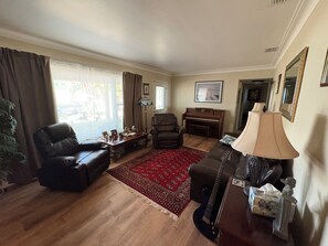 A living room with a piano, leather chairs, a red rug, and a lamp. - Charming 2-bedroom house in beautiful Clearwater with AC washer dryer (Clearwater)