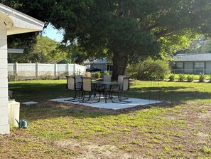 A patio with a table and chairs, a tree, and a white fence. - Charming 2-bedroom house in beautiful Clearwater with AC washer dryer (Clearwater)