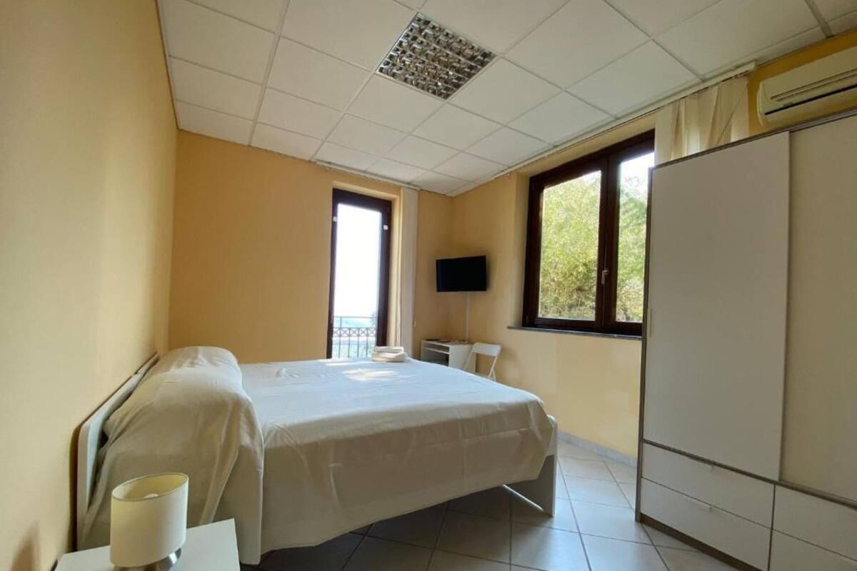 Una camera d'albergo con un letto, una televisione, un armadio e una finestra.