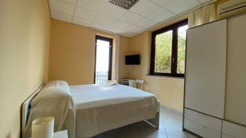 Una camera d'albergo con un letto, una televisione, un armadio e una finestra.