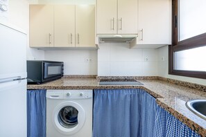 A compact kitchen with a washing machine, microwave, and a window. - Studio in aloha with front ocean view (Benalmádena)