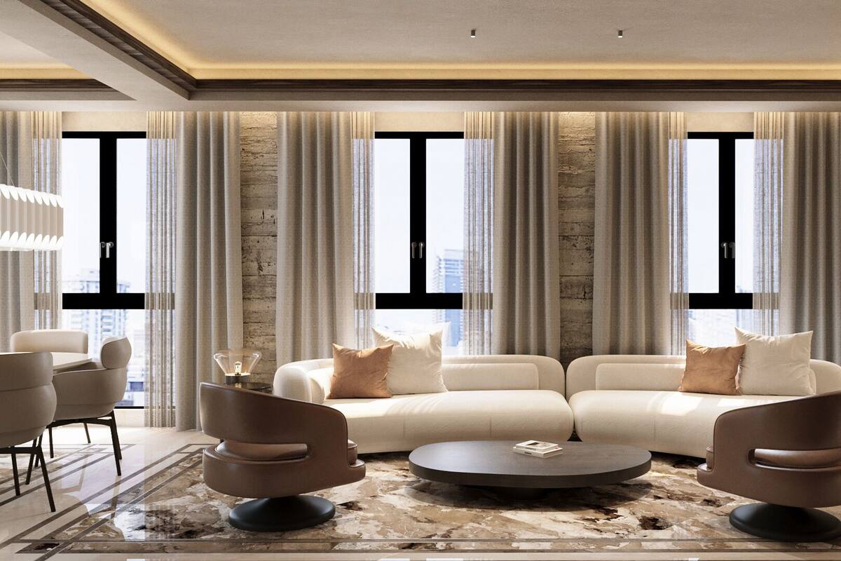 Un salon moderne avec un canapé d’angle, deux fauteuils, une table basse et de grandes fenêtres avec des rideaux.
