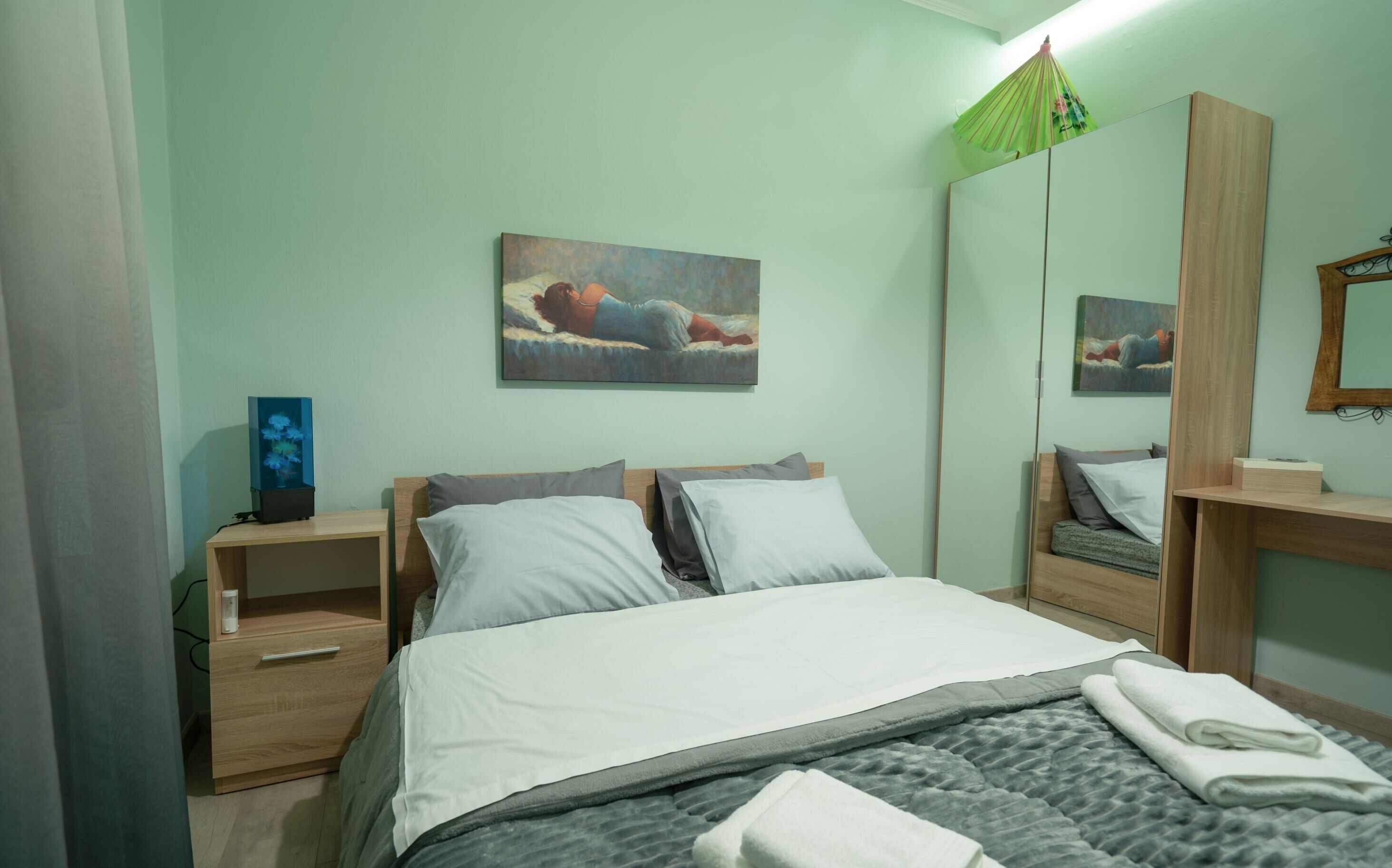 Un dormitorio con cama, mesitas de noche, un espejo y obras de arte en las paredes.
