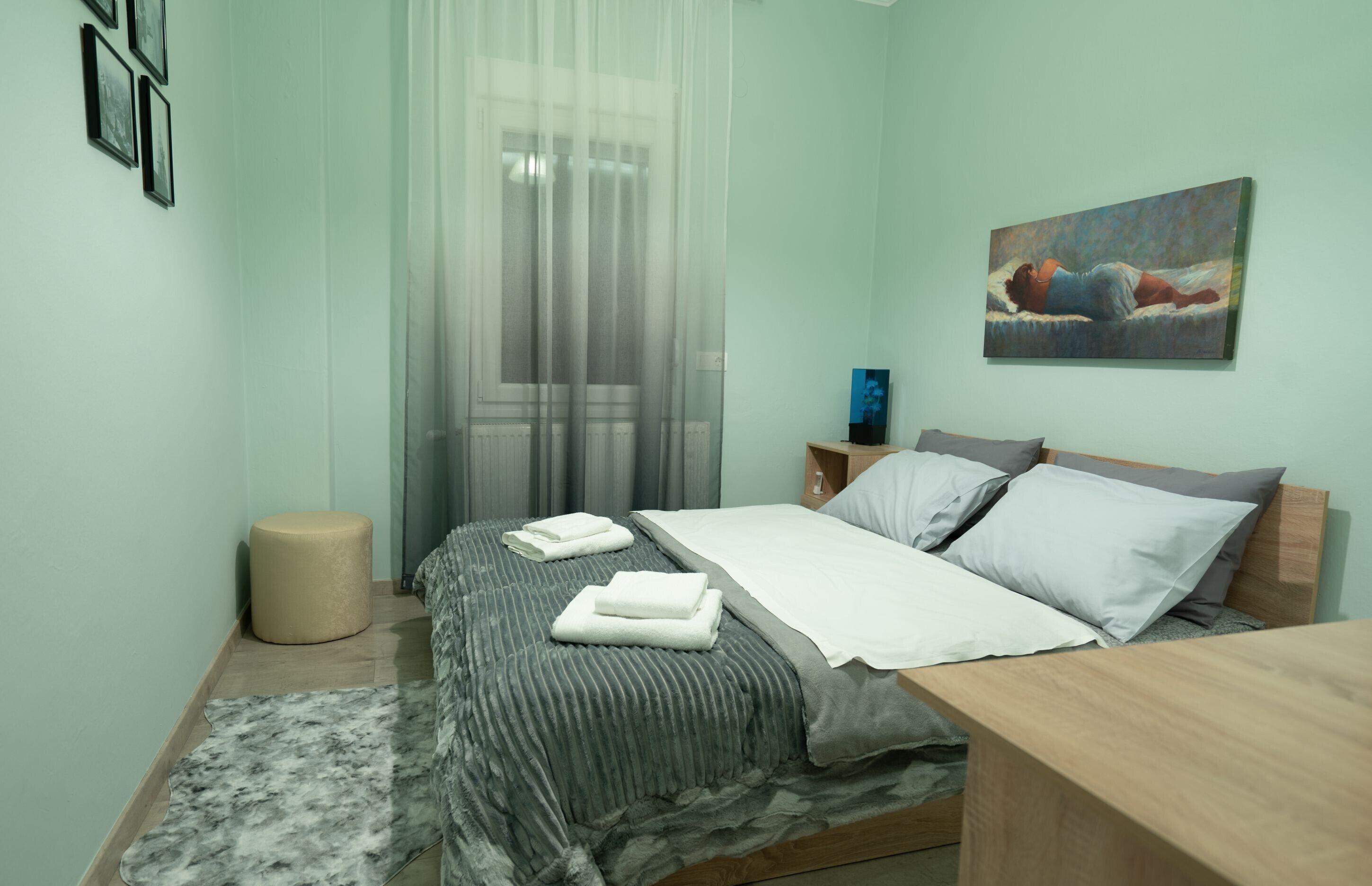 A neatly arranged bedroom with a bed, bedside table, and a painting on the wall.