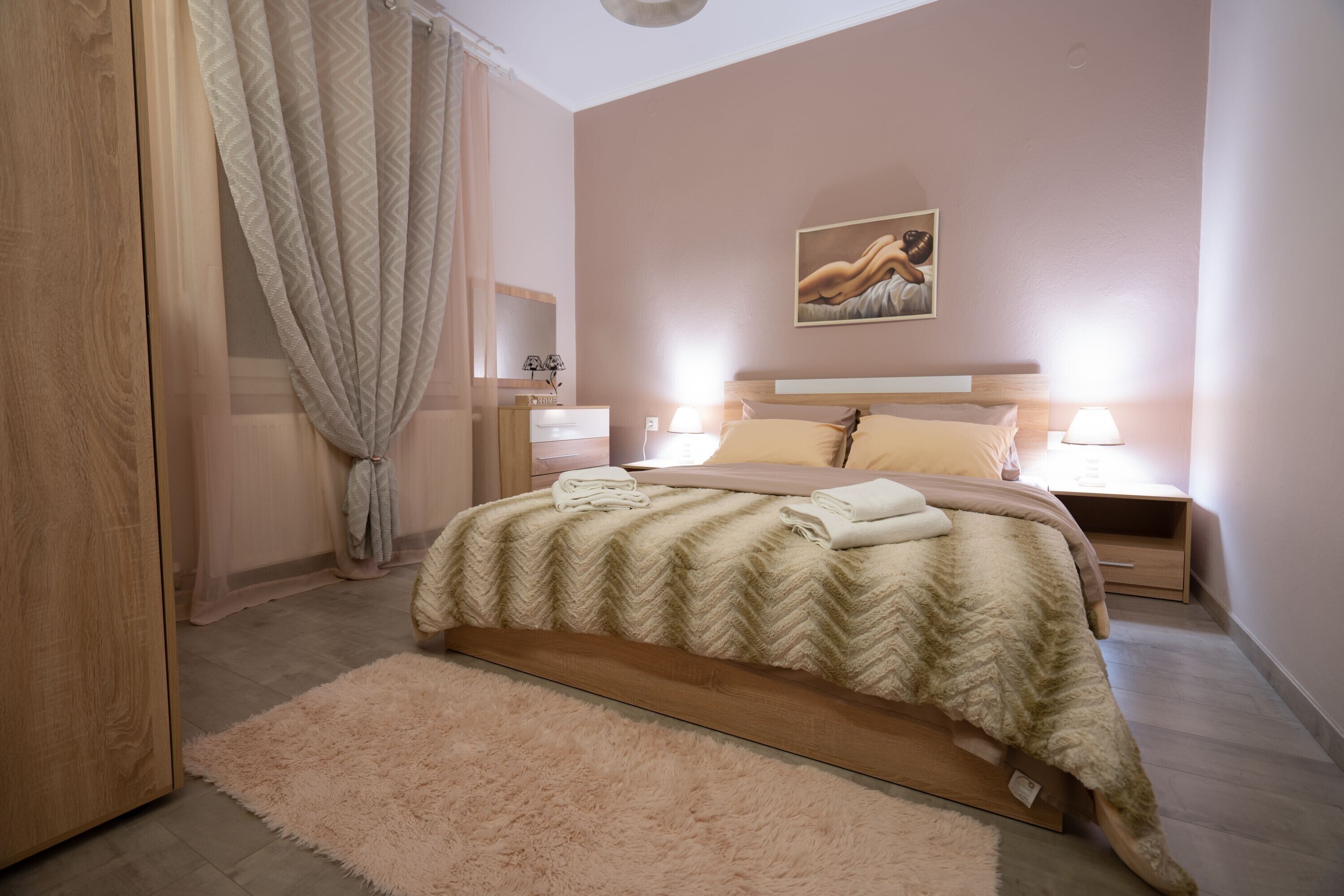 A bedroom with a bed, bedside tables, a nightstand, a fluffy rug, and a painting on the wall.
