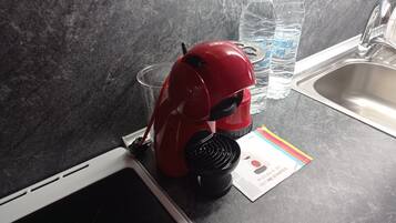 A kitchen with a red appliance, two water bottles, a glass, and a booklet on the counter.