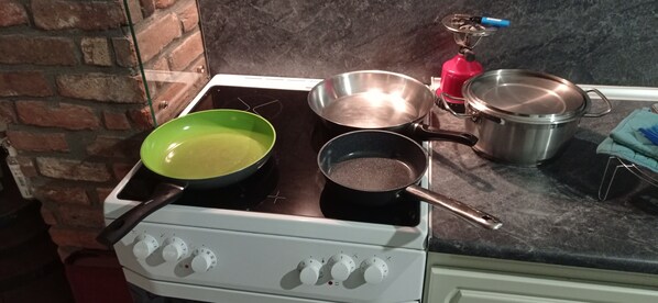 Una cocina con estufa, ollas y sartenes.