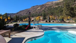 A swimming pool with lounge chairs and a view of a forested mountain. - Tamarron Treetop | AC, Pool, Hot Tub, Golf & Ski (Durango)
