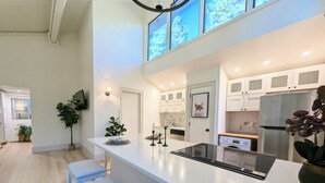 A modern kitchen with a central island, white cabinetry, and a large window. - Tamarron Treetop | AC, Pool, Hot Tub, Golf & Ski (Durango)