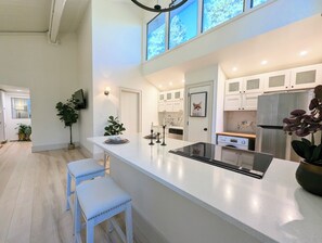A modern kitchen with a central island, white cabinetry, and a large window. - Tamarron Treetop | AC, Pool, Hot Tub, Golf & Ski (Durango)