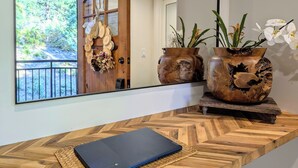 A wooden reception desk with a laptop, two wooden vases with flowers, and a door with a wreath. - Tamarron Treetop | AC, Pool, Hot Tub, Golf & Ski (Durango)
