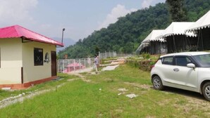A small building with a red roof, a white tent, and a parked car. - Kedarnath Eco Resort  (Ukhimath)