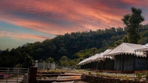 A series of tents set up in an open area with a forested hill in the background. - Kedarnath Eco Resort  (Ukhimath)