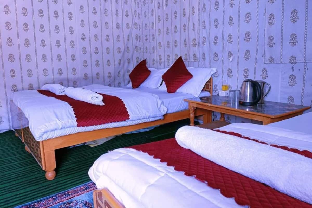 Ein Zimmer mit zwei Betten, einem Holztisch und einer Wand mit Muster.