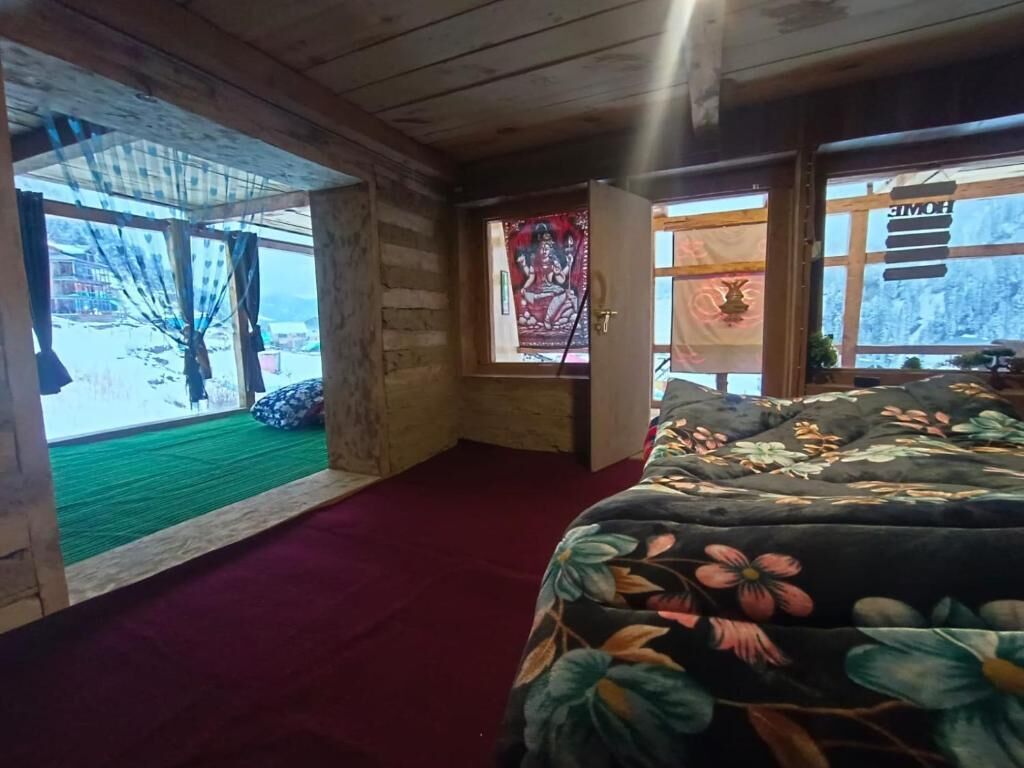 A room with a bed, a window with a view, and a door leading outside.