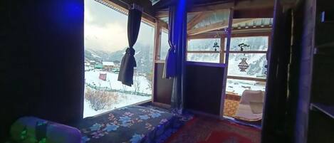 Ein Zimmer mit Blick auf schneebedeckte Berge, einer Holzbalkendecke und einem gemusterten Teppich.