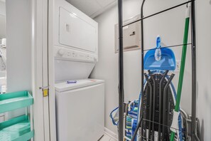 Ein Waschbereich mit Waschmaschine, Wäscheständer und einem Mopp.