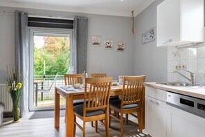 Une cuisine moderne avec un coin repas, une vue par la fenêtre et un petit jardin à l’extérieur.