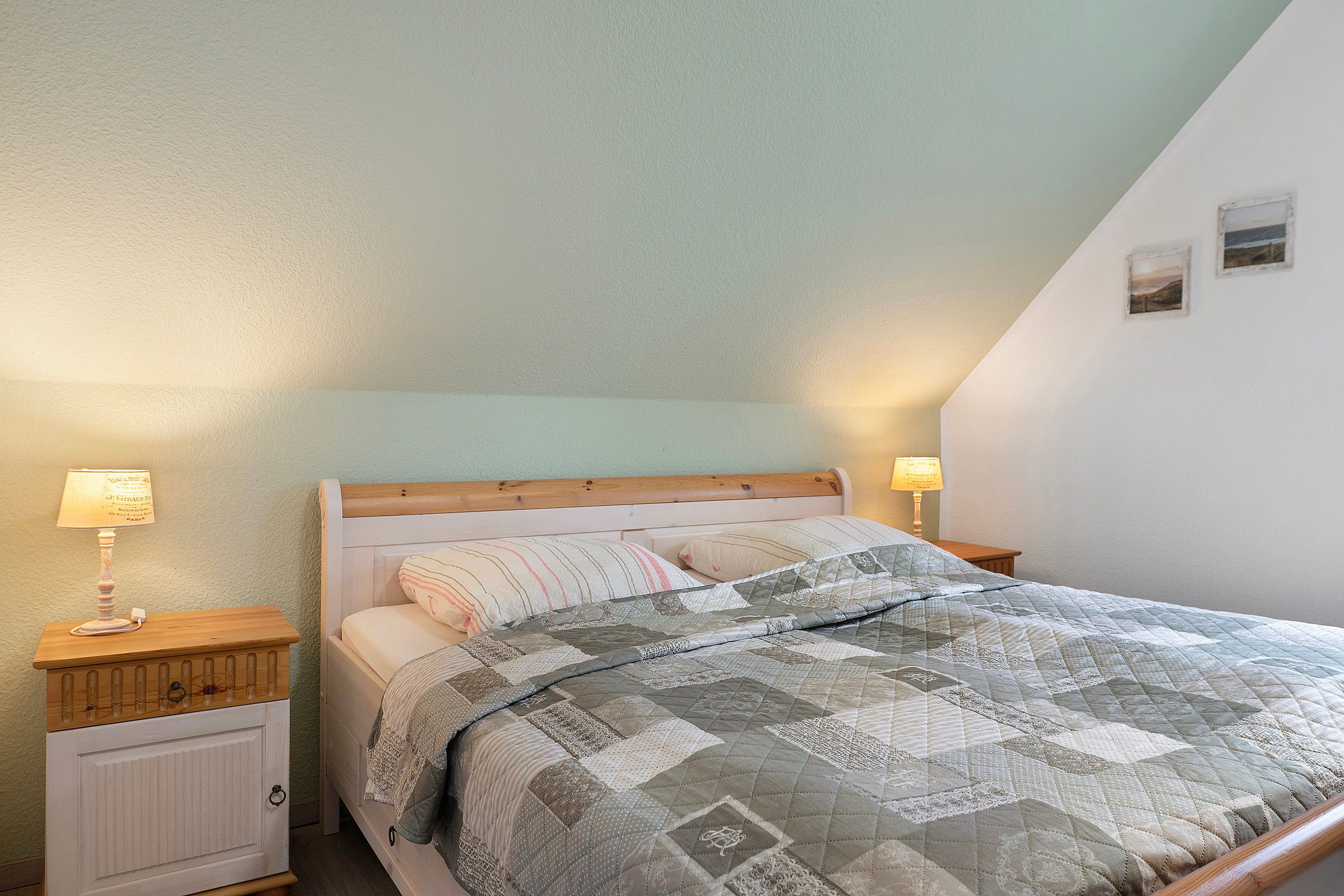 Une chambre à coucher avec une tête de lit en bois, une couvre-lit matelassée, deux lampes de chevet et une petite table de chevet avec une lampe.