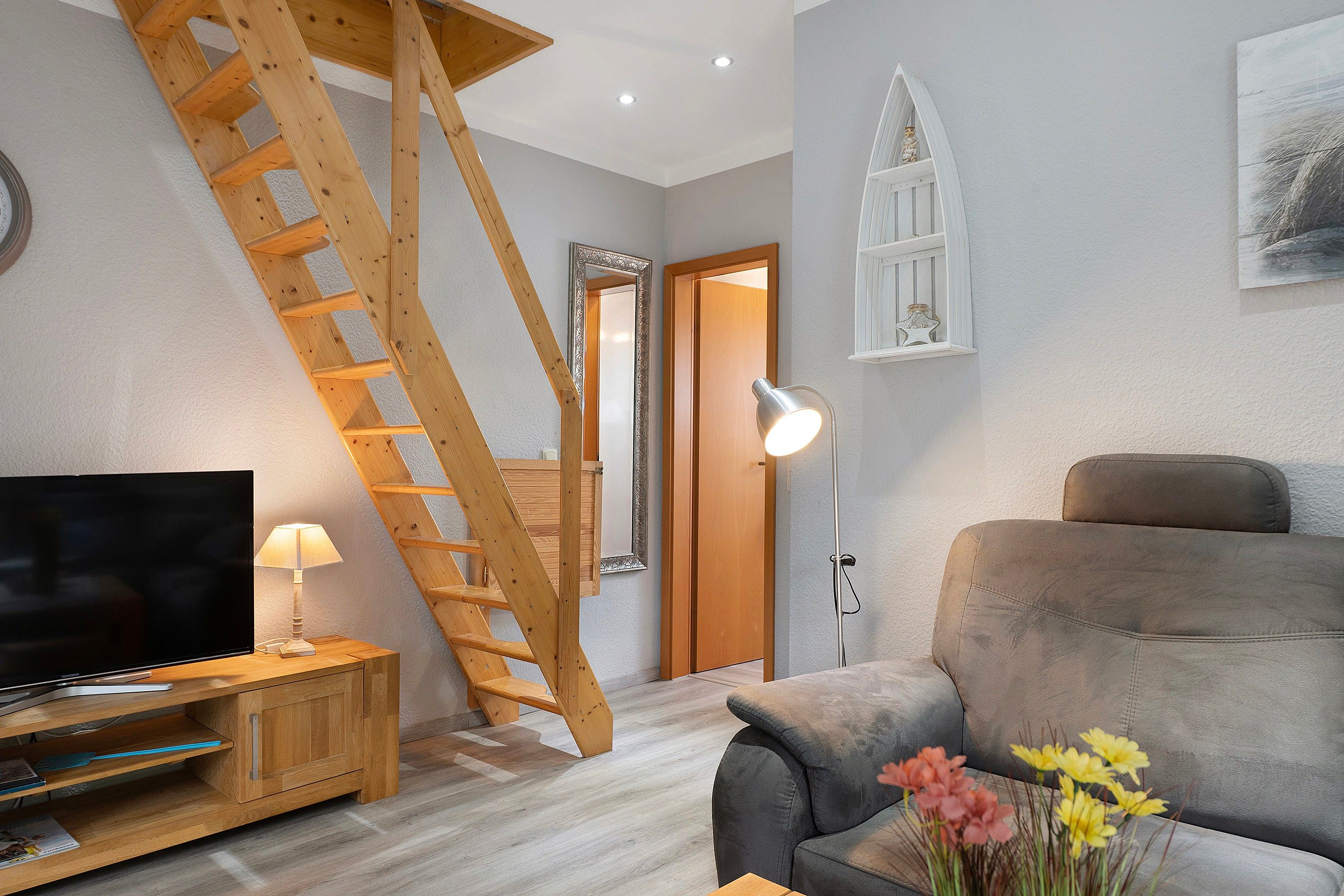 A living room with a wooden staircase, a television, a lamp, and a sofa.