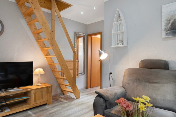 A living room with a wooden staircase, a television, a lamp, and a sofa.