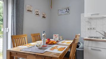A dining area with a wooden table, chairs, and a kitchen area with a sink and cabinets.