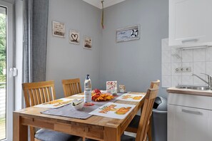 Ein Essbereich mit einem Holztisch, Stühlen und einer Küchenzeile mit Spüle und Schränken.