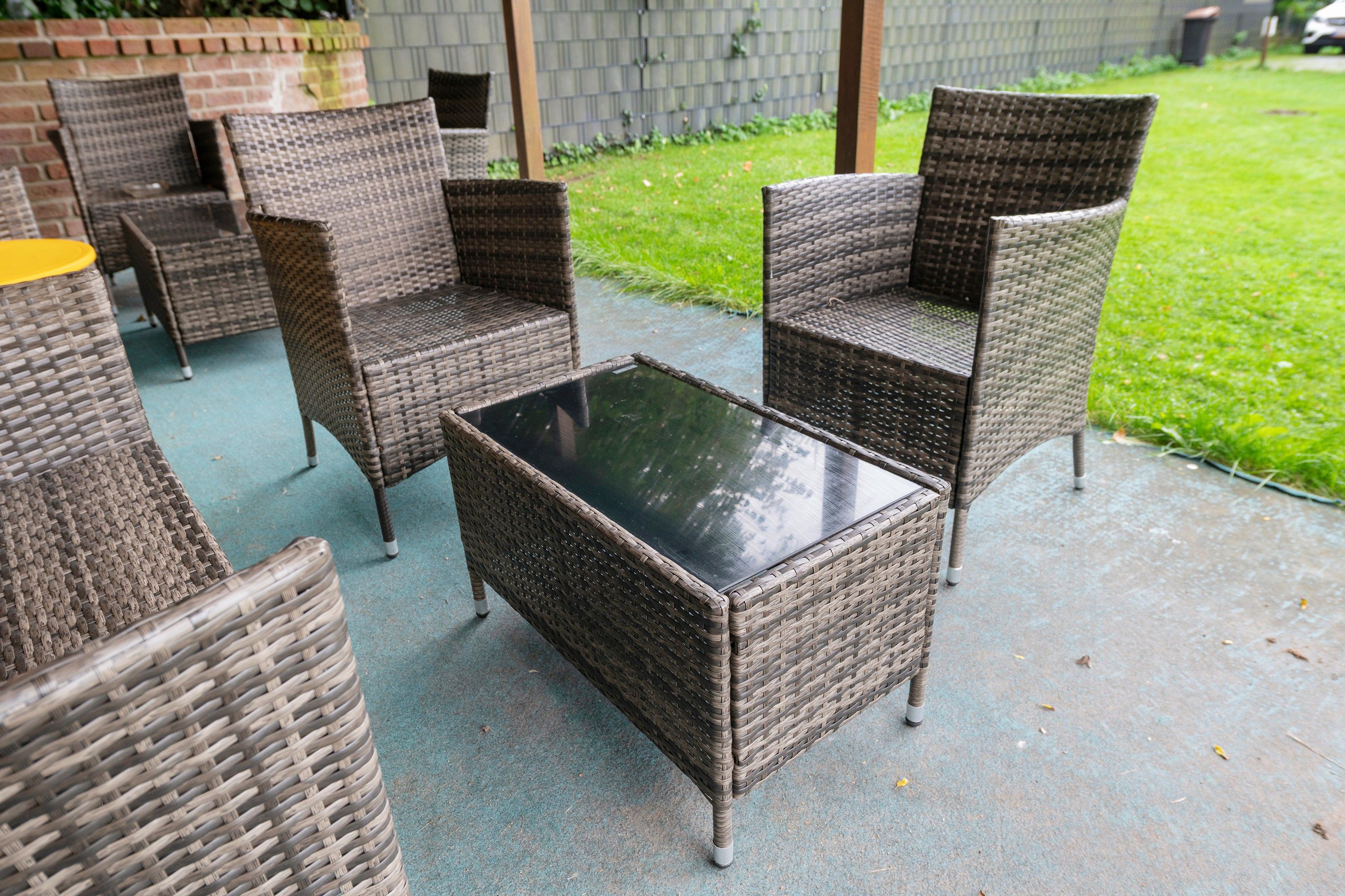 Eine Terrasse mit Korbmöbeln, darunter Stühle und ein Tisch.