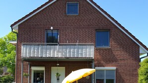 A two-story brick house with a covered patio, a wooden bench, and a small pool.
