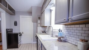 Una cucina con piano cottura, forno, lavello e pensili.