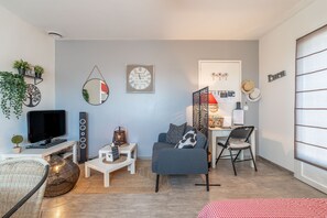 Un salon comprenant un canapé, un téléviseur, des haut-parleurs et un miroir décoratif.