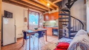 Un espacio habitable compacto con cocina, comedor y una escalera en espiral.